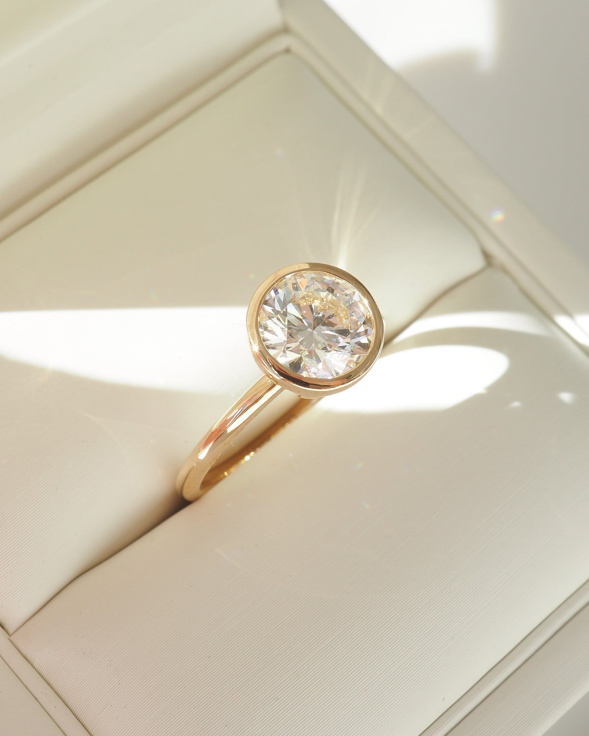 Gold bezel solitaire engagement ring with round brilliant center stone