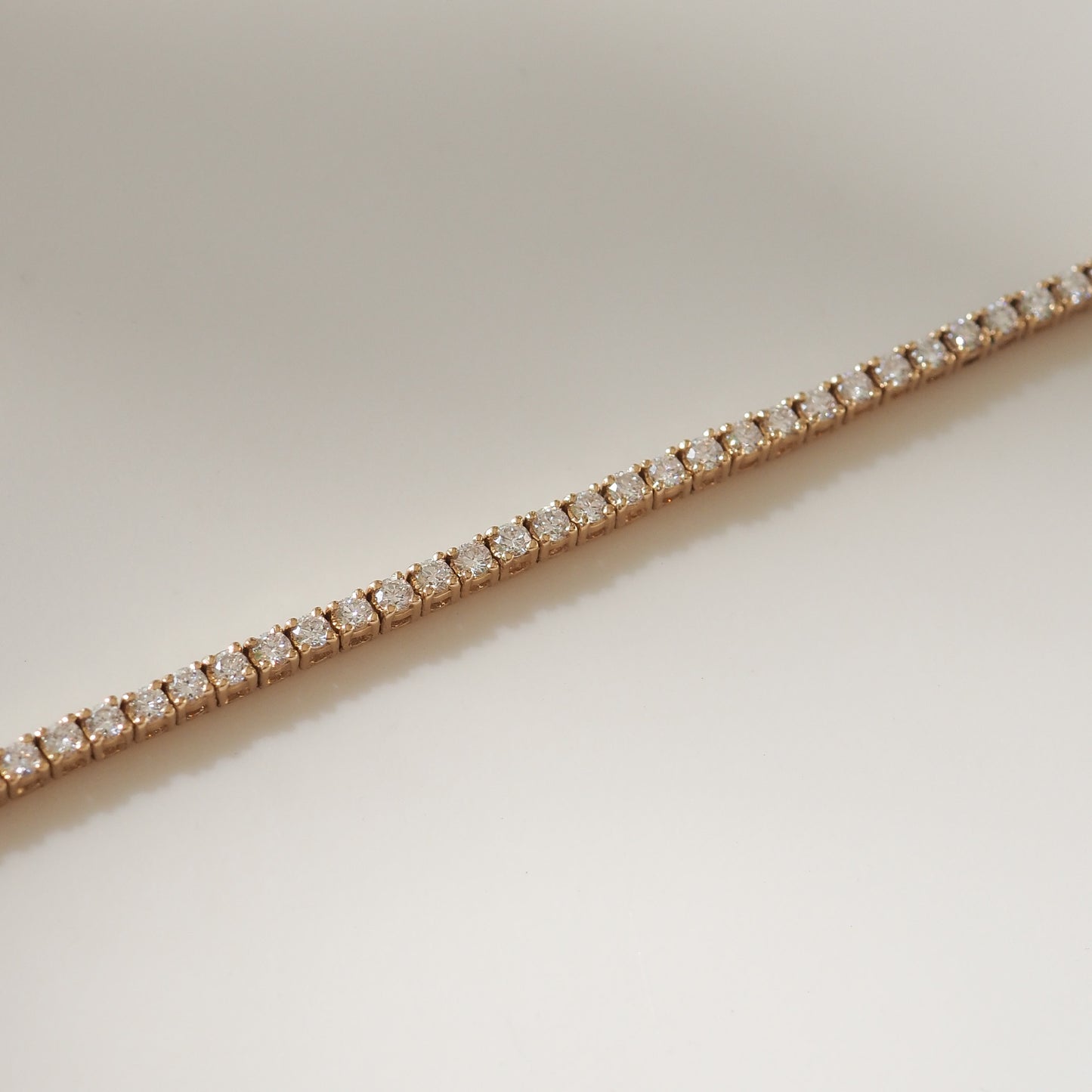 Yellow gold bracelet with diamonds on a light beige background
