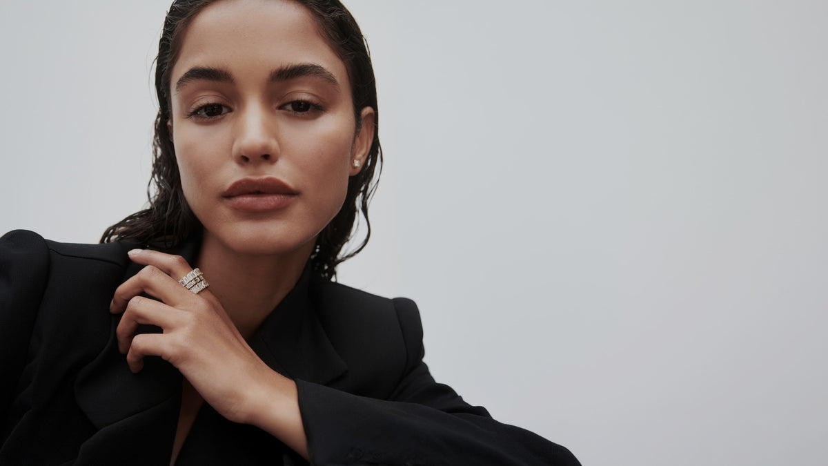 Model wearing a stack of yellow gold diamond bands featuring mixed diamond cuts with a grey backdrop