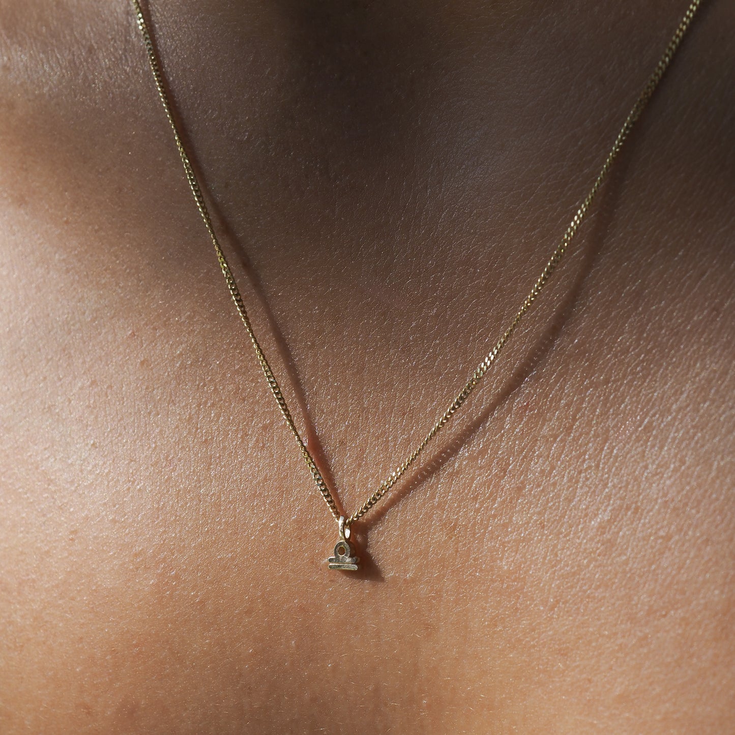 The Libra Zodiac Necklace highlights the Libra symbol among a yellow gold chain.[text overlay: Libra] [text colour: #000000]
