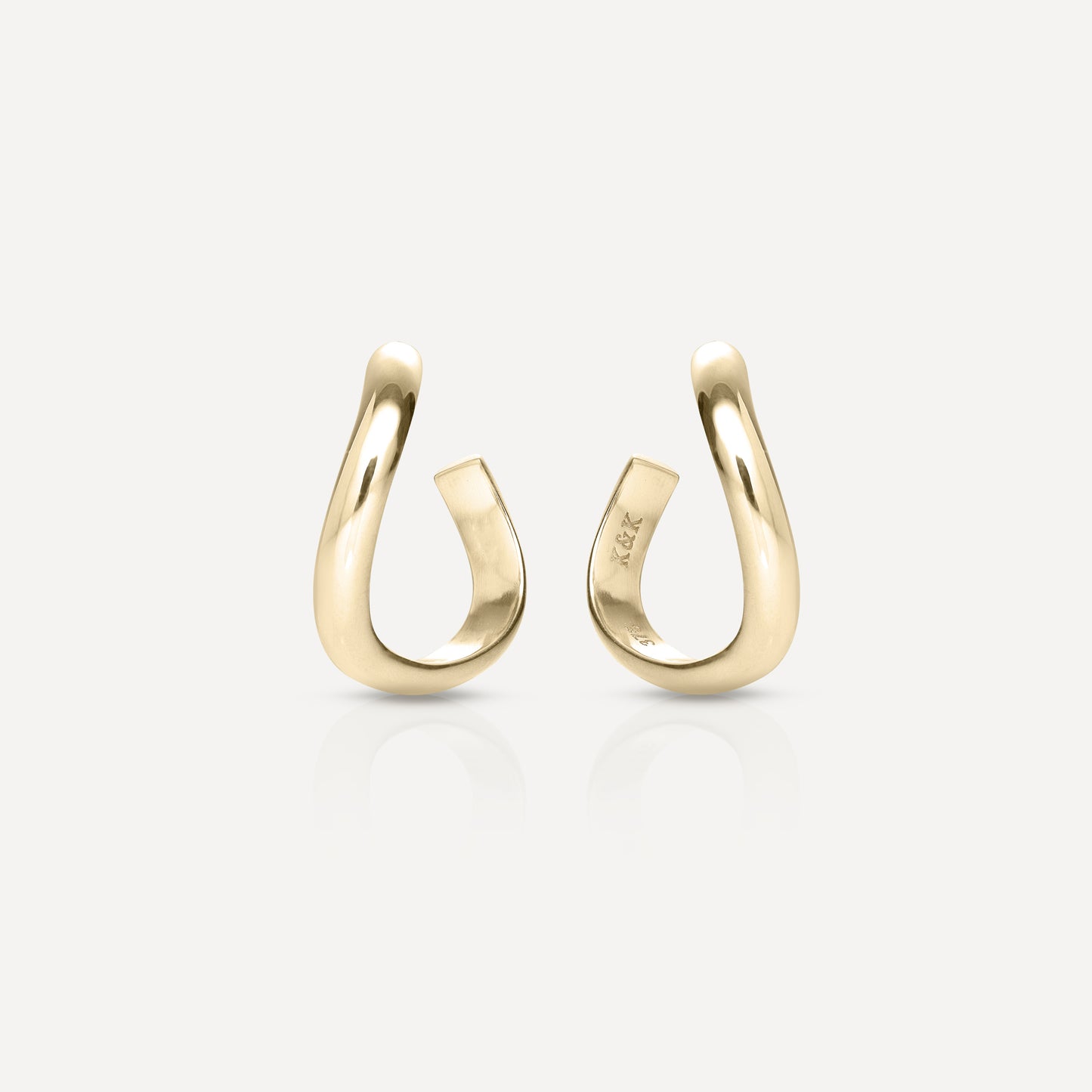 Pair of elegantly curved gold open hoop earrings on a white background, showcasing luxury jewellery design and craftsmanship.