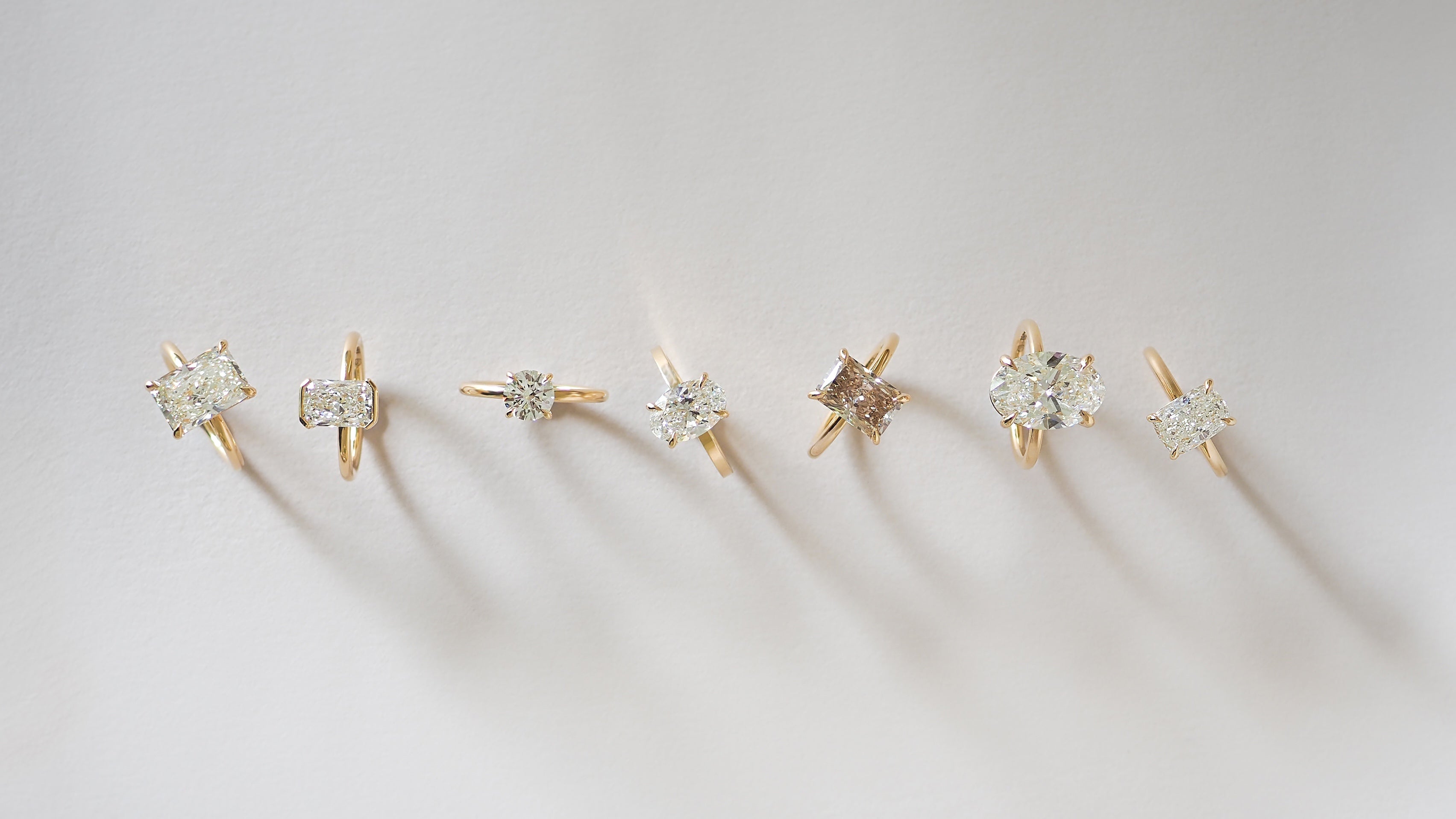 Set of gold and diamond engagement rings on a light grey background